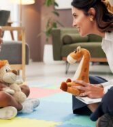 Psychology, woman and girl with dolls, talk and happy with clipboard for emotional assessment on floor. Person, therapist and child with toys, playful and checklist for test at mental health clinic